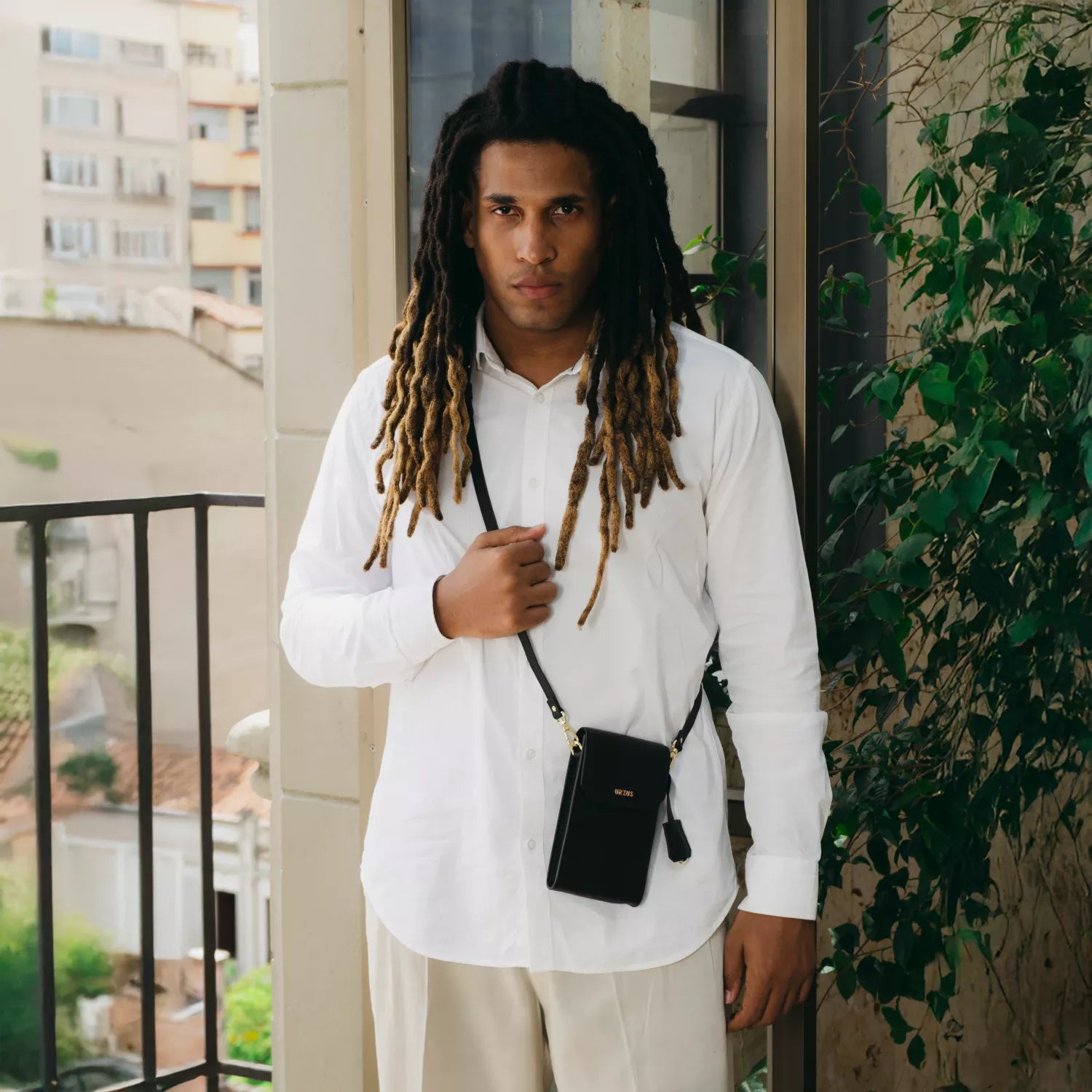 Hombre con camisa blanca llevando el Boreal Bolso Cruzado Compacto en cuero negro de Urzus, perfecto para portar billetera, celular y documentos con practicidad